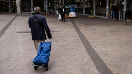 Una jubilada con un carrito de compra entrando en un mercado municipal de Barcelona