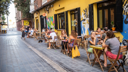 La gente se sienta afuera de una cafetería en una zona peatonal en Valencia, España.