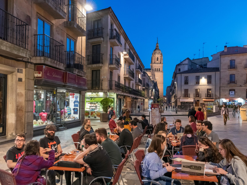 Estudiantes en un café por la noche en la Calle Rúa Mayor mirando hacia la torre de la Catedral Vieja, Salamanca