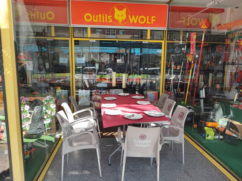 Una mesa preparada para comer en el portal de un establecimiento de venta de maquinaria agrícola