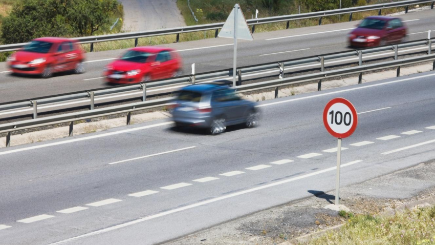Coches pasando la señal de límite de velocidad de 100 kilómetros por hora en una autopista en España