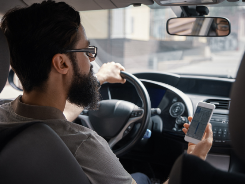 Hombre consulta móvil al volante