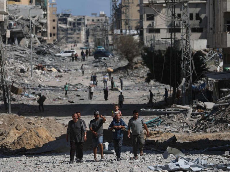 . Palestinos caminan por una calle entre los escombros de los edificios destruidos durante un alto el fuego entre Israel y Hamás, en el marco de la primera fase del plan de paz para Gaza, en la Ciudad de Gaza, Franja de Gaza