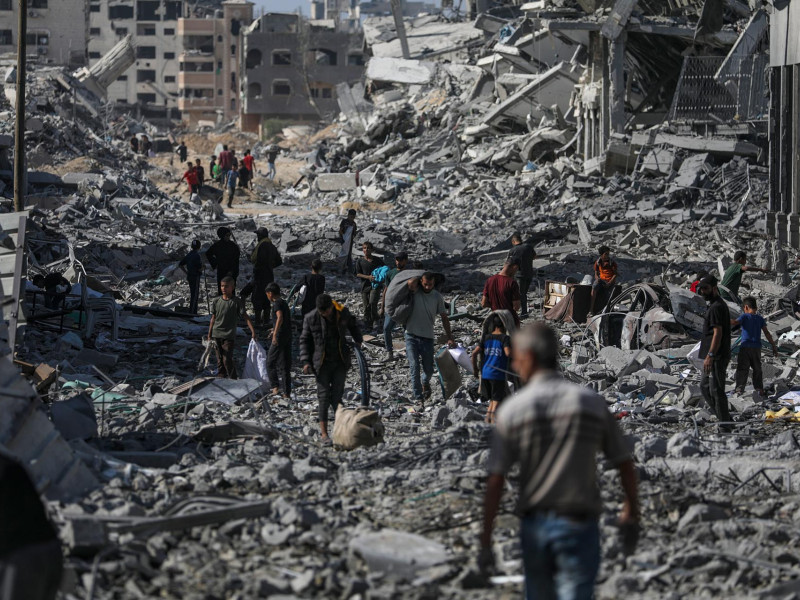 Palestinos caminan por una calle entre los escombros de los edificios destruidos durante el alto el fuego entre Israel y Hamás