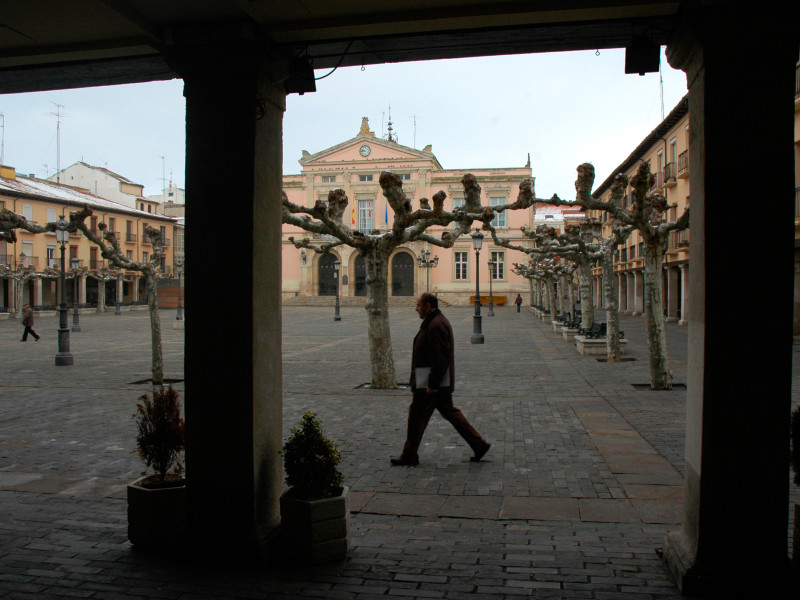 Un jubilado anda por la Plaza Mayor y el Ayuntamiento de Palencia