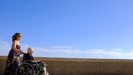 Una mujer empuja a una jubilada en silla de ruedas en Cádiz