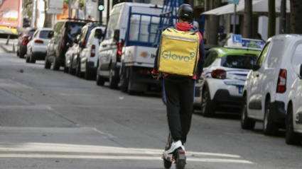 Un repartidor en patinete eléctrico por el centro de Badalona