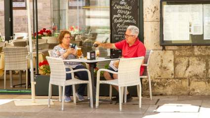 Una pareja de jubilados disfruta de una bebida en un bar con terraza en la ciudad española de Burgos