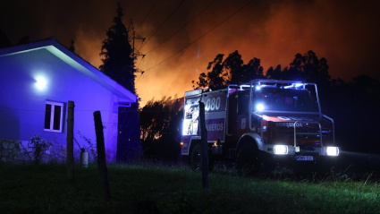 Un camión de Bomberos de Gijón, junto a una vivienda, en las labores de extinción del incendio forestal en el Monte Areo