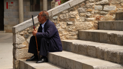 Jubilado sentado en las escaleras del casco antiguo de Girona