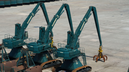 Las excavadoras de orugas de color verde árbol de la empresa Mantsinen, utilizadas para el manejo de chatarra, están estacionadas en el puerto.