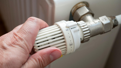 Una mujer regula la temperatura de un radiador