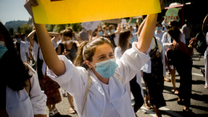 En Barcelona, una mujer con mascarilla sostiene una pancarta durante una marcha del MIR (Médicos Residentes) que exige mejoras en las condiciones laborales y un aumento salarial.