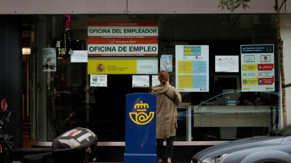 Mujer frente a una oficina de empleo (SEPE) leyendo los carteles expuestos en el escaparate en Madrid