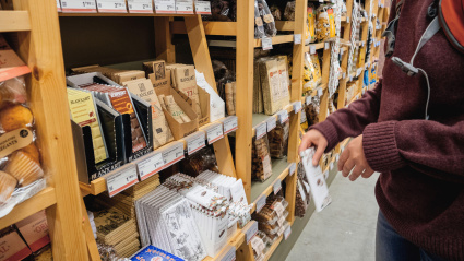 Una mujer elige chocolate negro y con leche catalán tradicional ecológico en la sección de dulces de una tienda de alimentación ecológica local.
