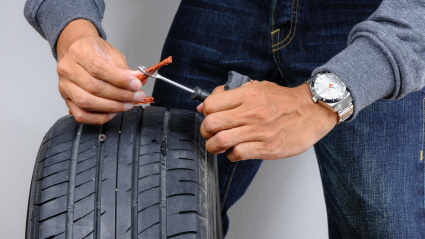 El hombre reparando un neumático pinchado con un kit de reparación.
