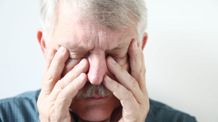 Jubilado apretando su nariz con los dedos