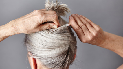 Mujer con canas haciéndose un moño