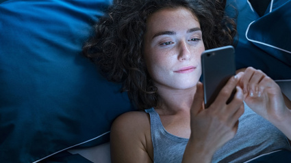 Una chica usa el teléfono en la cama