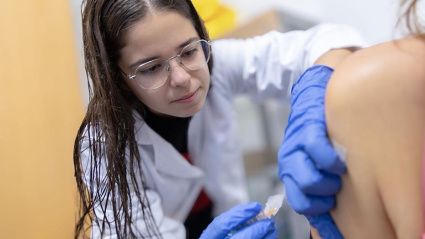 Una profesional sanitaria administra una vacuna a una paciente