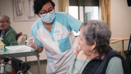 Una mujer jubilada recibe la vacuna contra la gripe