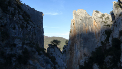 La brecha de Foz de Escalate en los altos escarpes rocosos debido a la erosión hídrica junto al lago de La Pena, con árboles sobre las rocas, al atardecer, en Aragón, España
