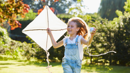 FGPEW7 Enthusiastic girl running with kite in sunny garden