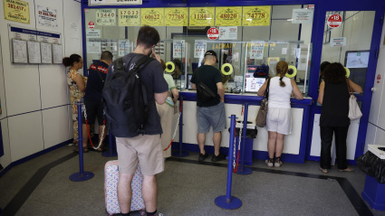Varias personas hacen cola en una administración de Lotería en Madrid