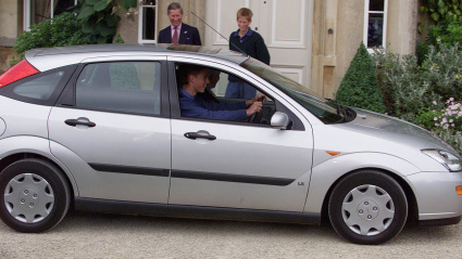 El príncipe Guillermo recibe una lección de conducir en Highgrove, julio de 1999. El príncipe Guillermo, de 17 años, conduce un Ford Focus con el instructor de policía Chris Gilbert en Highgrove Estate. El príncipe Harry y el príncipe Carlos observan.