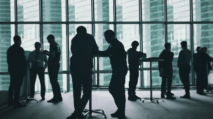 Personas interactuando en un centro de negocios con un ventanal de fondo.