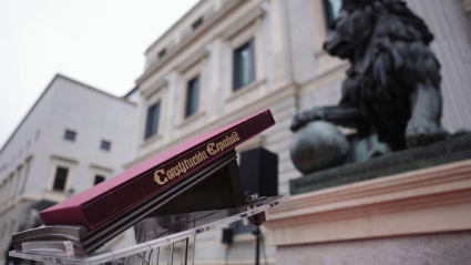 Ejemplar de la Constitución Española colocado ante los leones que custodian la entrada principal del Congreso de los Diputados antes del acto institucional por el Día de la Constitución