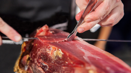 Maestro loncheador cortando jamón ibérico. Corta las lonchas con pinzas.