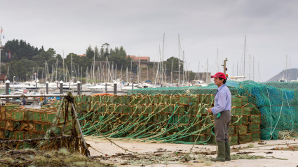 Un pescador desconocido repara redes de pesca en el puerto de Baiona