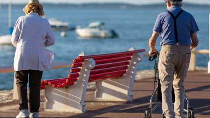 Jubilados con un andador con ruedas mirando el mar