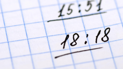 Los números repetidos de horas espejo están escritos a mano en una hoja de papel cuadriculada.