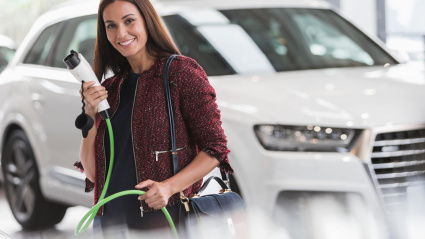 Mujer sosteniendo un cable de carga híbrido en la sala de exposición de un concesionario de automóviles