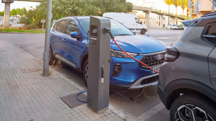 Dos coches eléctricos se están cargando en una estación pública en una acera de la ciudad. en Inca