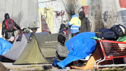 GRAFCAT5902. BADALONA (BARCELONA) (ESPAÑA), 18/12/2025.- Aspecto este jueves del espacio donde el medio centenar de personas que fueron desalojadas ayer del antiguo instituto B9 de Badalona (Barcelona) han pasado la noche, una plaza que se encuentra delante del edificio desocupado, donde han instalado una decena de tiendas de campaña.EFE/ Alejandro García