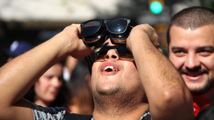 Un hombre mira hacia el sol, con varias gafas en las manos
