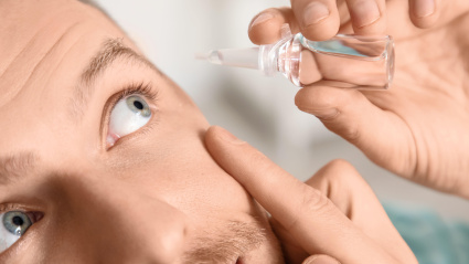 Hombre joven usando gotas para los ojos en casa, primer plano