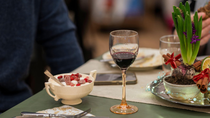Mesa festiva con postre de invierno, vino tinto y decoración navideña. Acogedora cena navideña con un toque de frutos rojos y vino caliente.