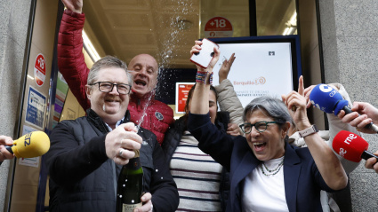 Varias personas celebran a las puertas de la administración de loterías del número 10 de la calle Barquillo, en Madrid