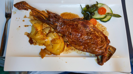 Pierna de cordero lechal, ensalada, patatas laminadas, servida en plato cuadrado en la terraza del restaurante Palomeque, Zaragoza