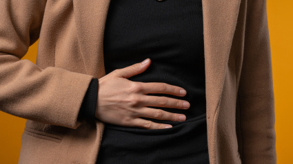 American student woman squeezing belly with hands because of abdominal pain. Lady suffering from stomach ache. Healthcare, problem with menstrual period cramps or bowel flatulence concept