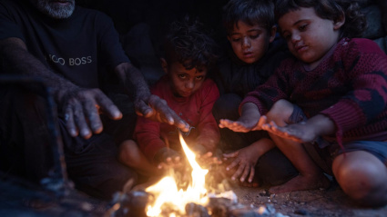Una familia palestina se calienta junto a una fogata frente a su refugio en la ciudad de Khan Younis, en el sur de la Franja de Gaza