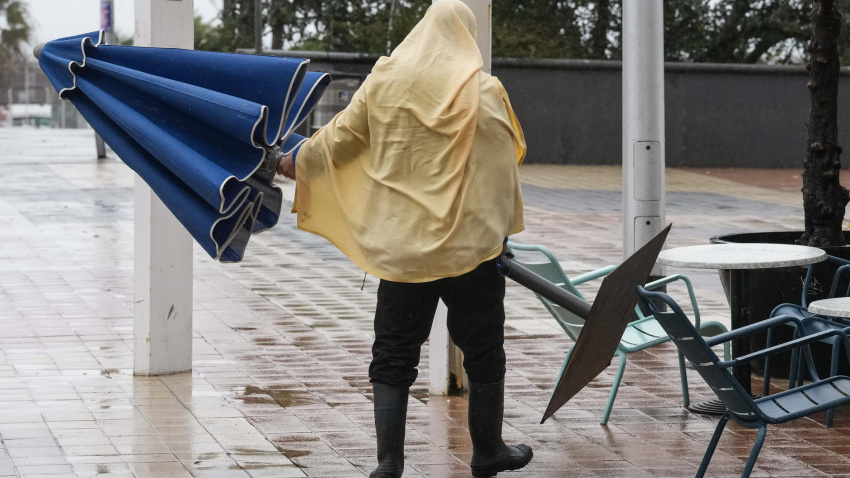 Un hostelero recoge la terraza para protegerse de la lluvia