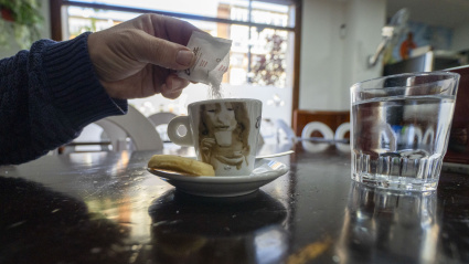 Un cliente echando un sobre de azúcar al café en una barra de bar