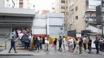 Personas hacen fila en un supermercado para abastecerse este sábado en Caracas