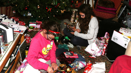 Chicas abriendo regalos de Navidad bajo el árbol de Navidad