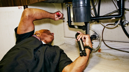 Fontanero trabajando debajo del fregadero